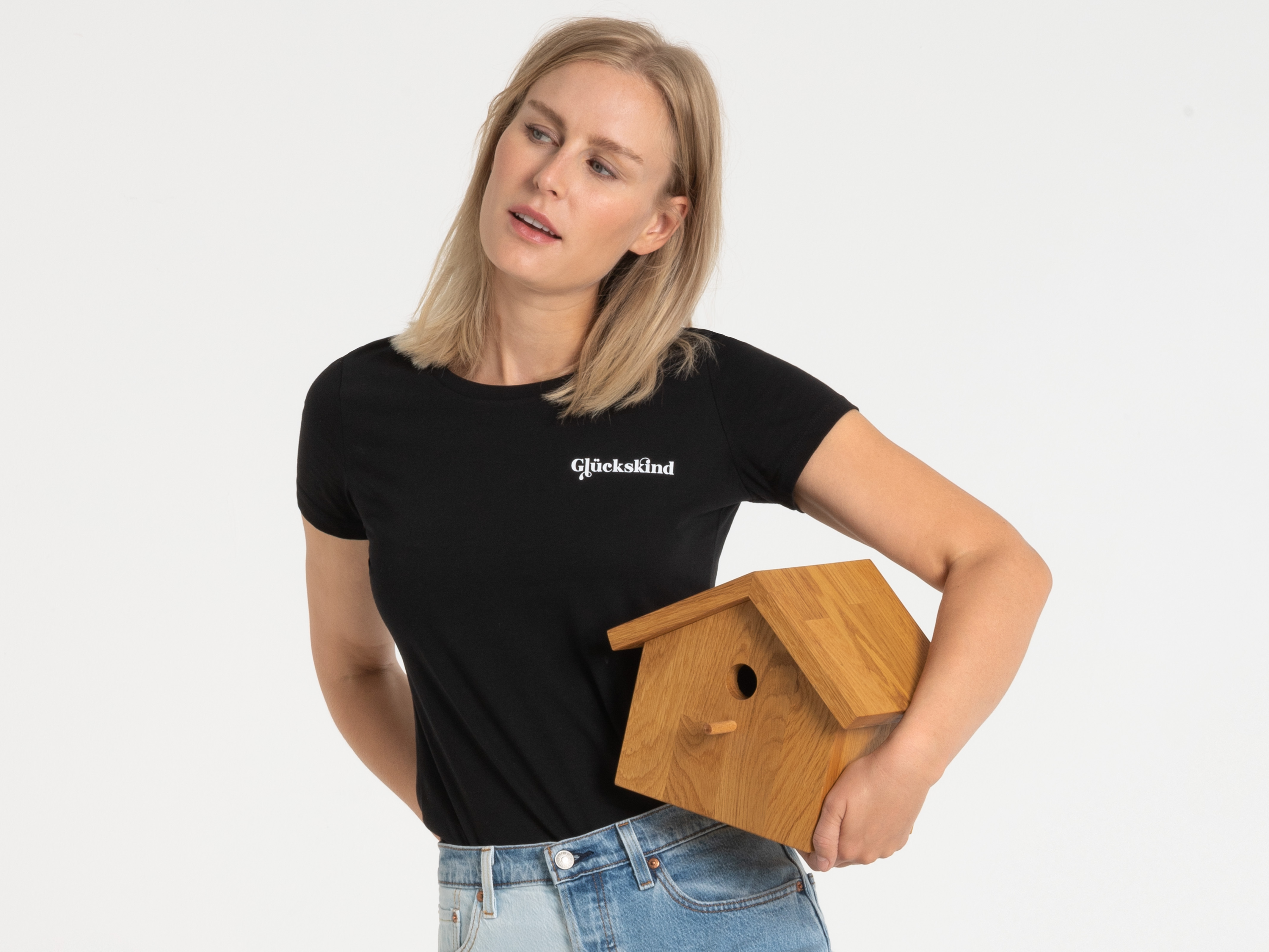Frau im schwarzen T-Shirt zeigt Stoffbeutel – modisches Accessoire kombiniert mit schlichtem Shirt.