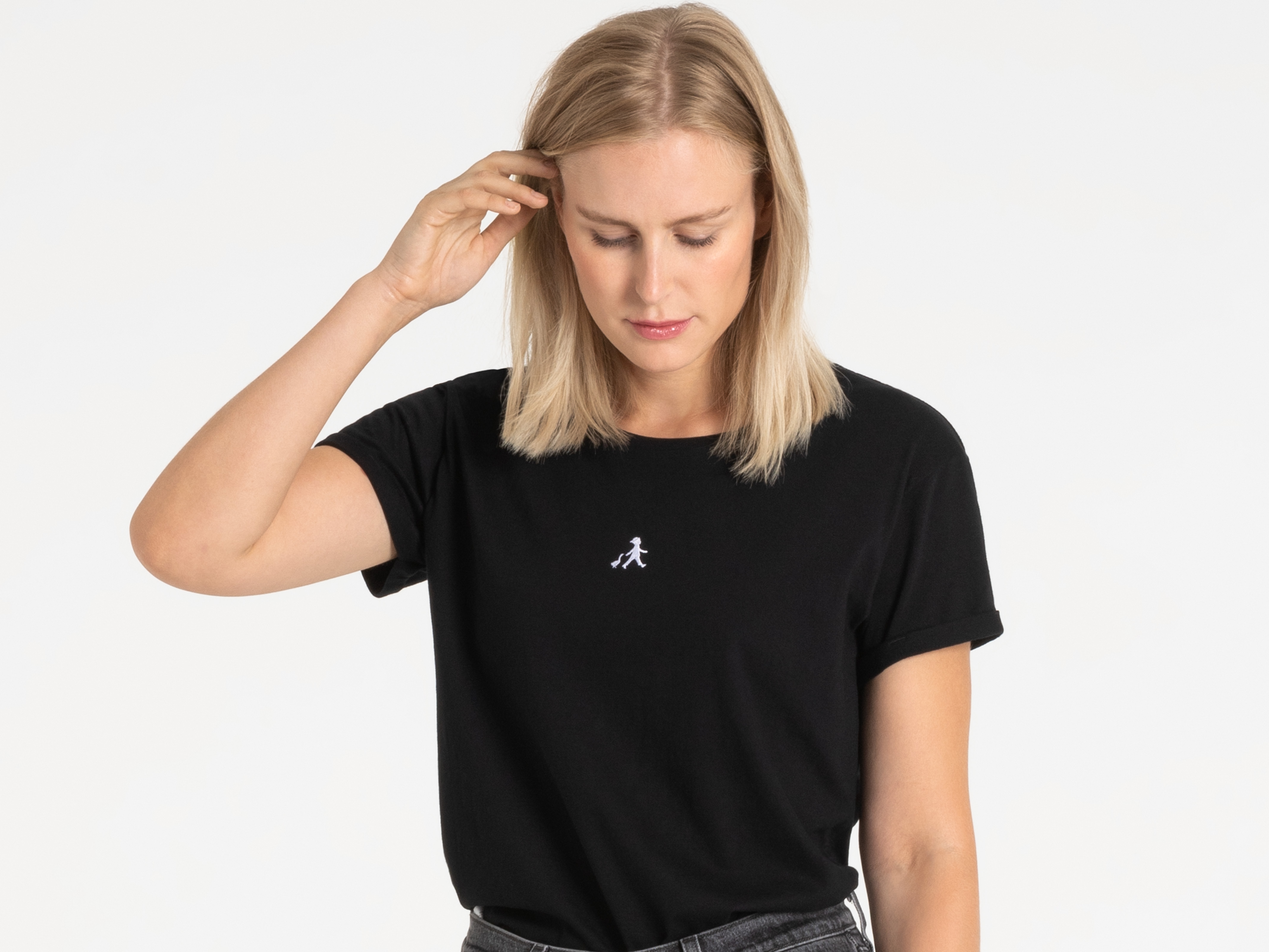 Frau mit schwarzem Shirt greift sich ans Haar – natürlich und sympathisch.