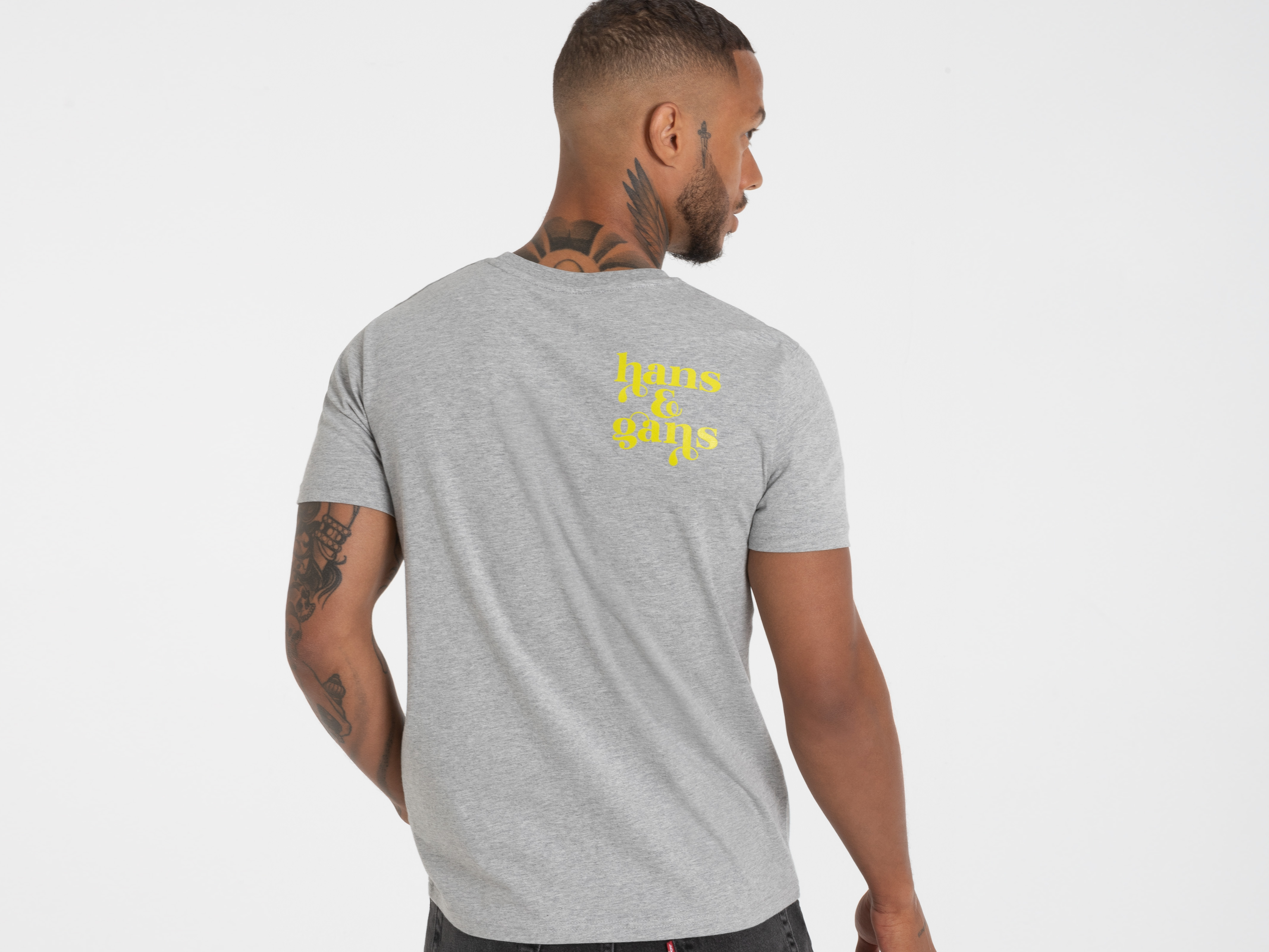 Rückansicht eines Mannes im grauen Shirt mit großem gelben Rückendruck – modernes Statement-Piece