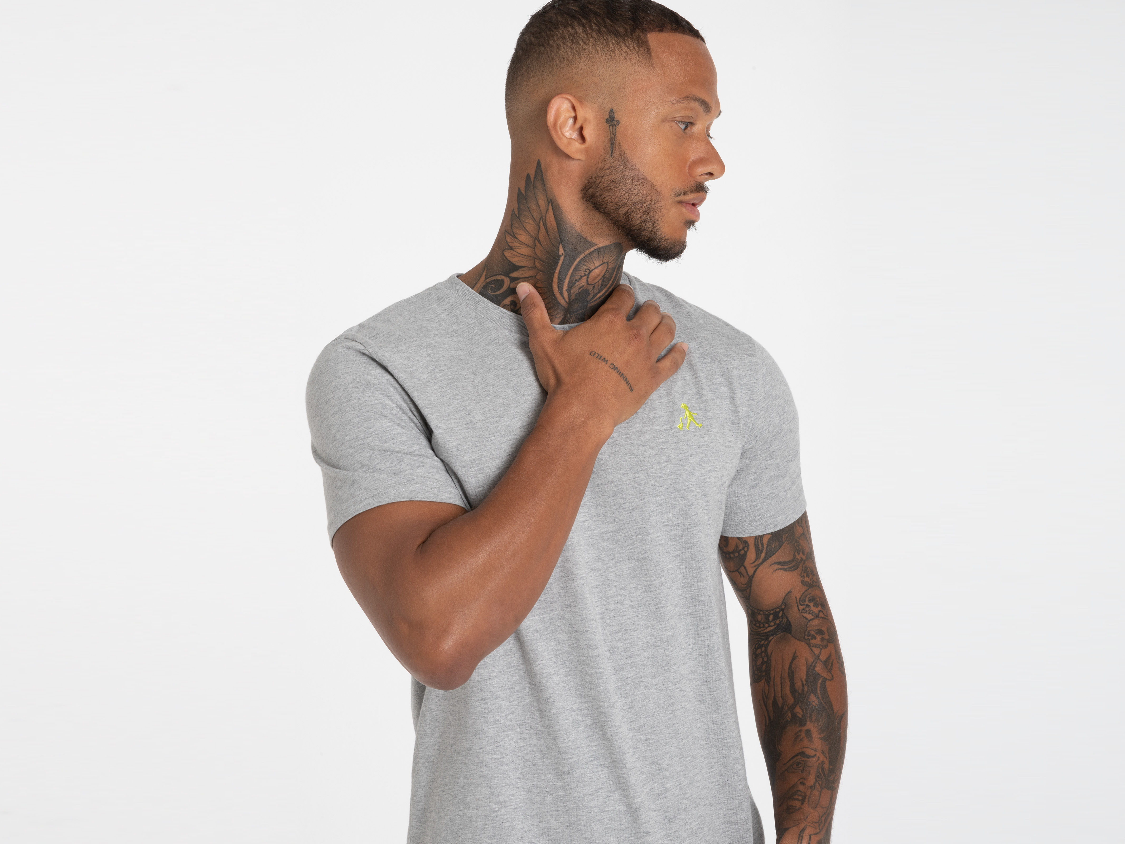 Seitlicher Blick auf Mann im grauen Shirt, Logo vorn – cleanes Design trifft Charakter.