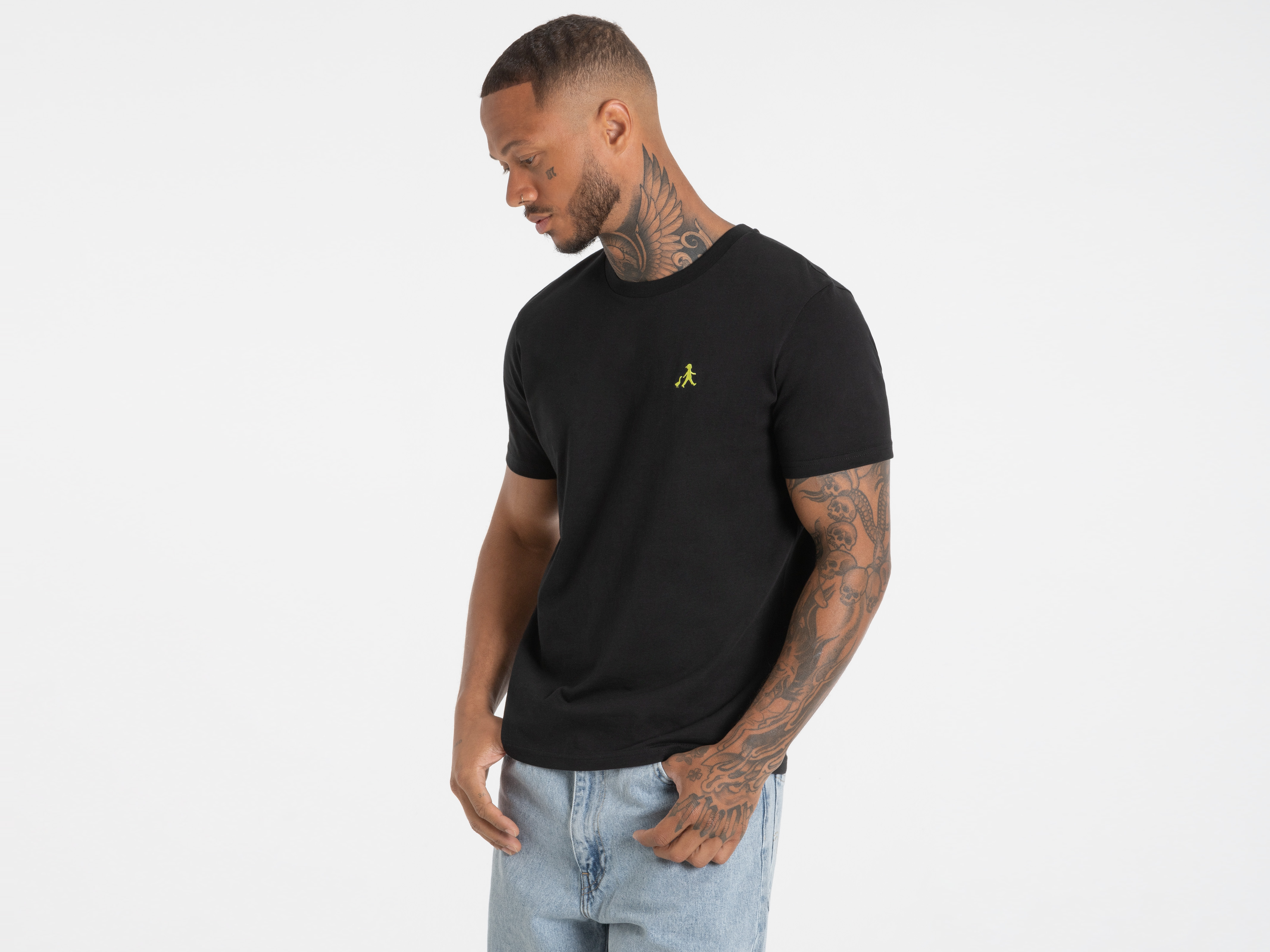 Seitlicher Blick auf Mann im schwarzen T-Shirt mit dezentem Frontlogo – cleanes, urbanes Design.